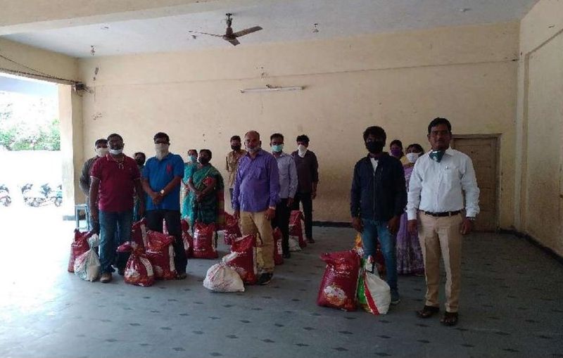 Volunteers standing beside sacks of ration kits ready for distribution